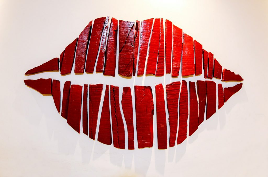 Abstract artwork of red lips created from sliced wood planks on a white background, symbolising the iconic imagery of The Rocky Horror Show.